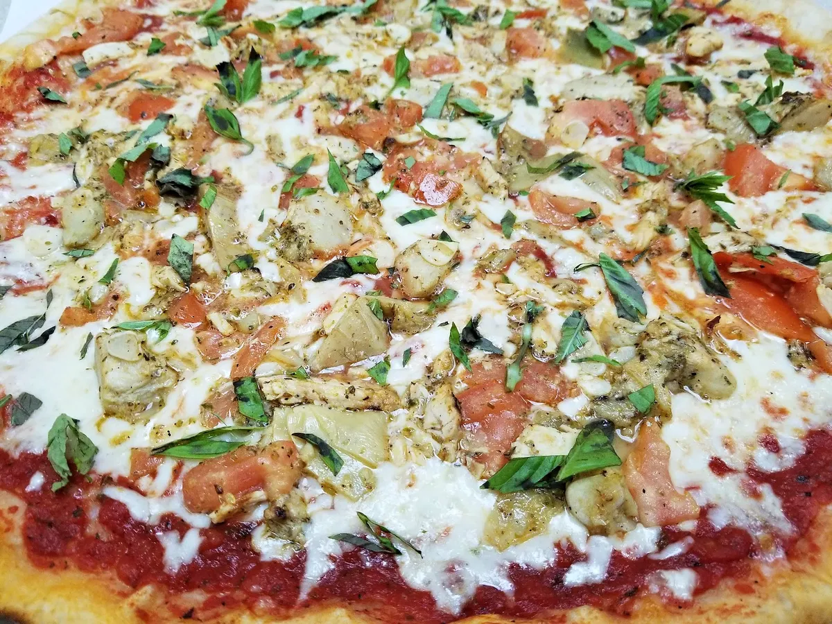 A pizza with chicken, artichoke and basil
