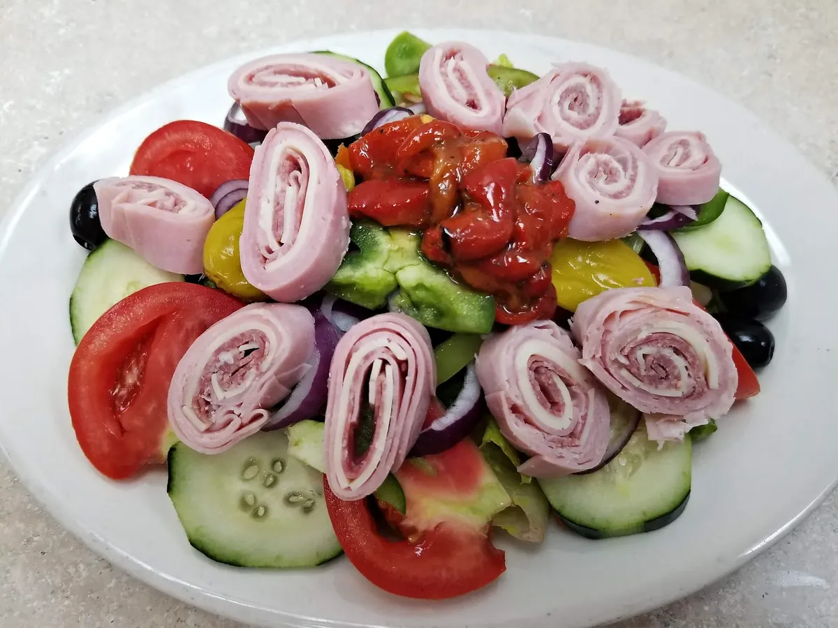 An antipasto salad with rolled ham and salami