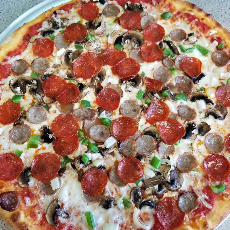 A round pizza loaded with pepperoni, sausage, mushrooms and green peppers