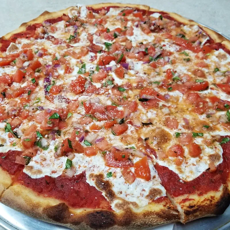 A bruschetta pizza with chopped tomato over fresh mozzarella