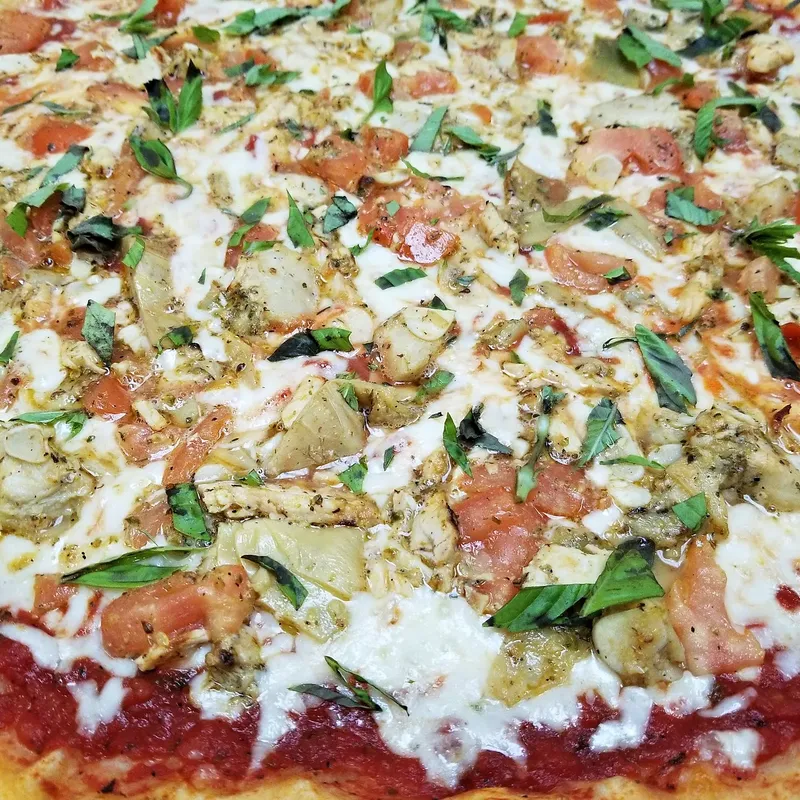 A pizza with chicken, artichoke and basil