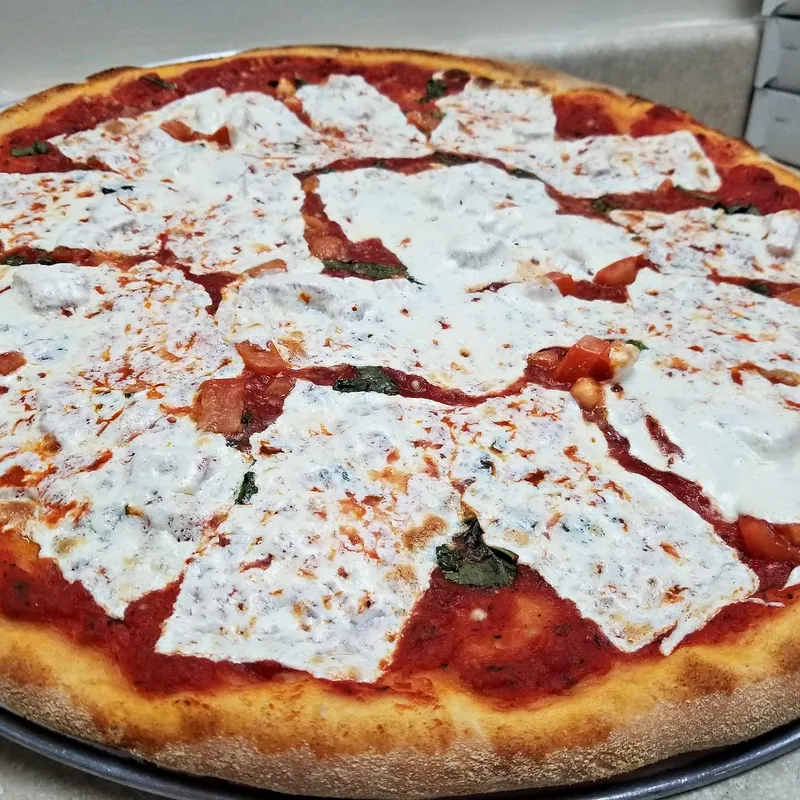 A margherita-style pizza with squares of fresh mozzarella on red sauce and basil