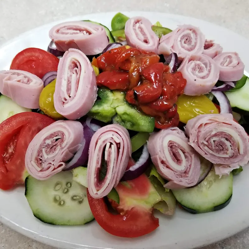 An antipasto salad with rolled ham and salami