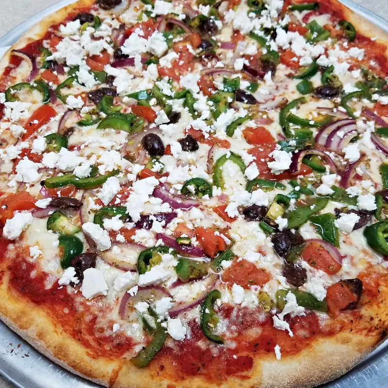 A vegetable pizza with feta, peppers and red onion on the tray